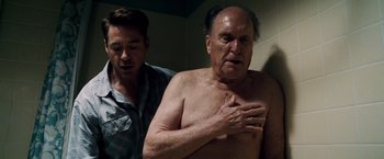 Movie still from “The Judge” (2014), directed by David Dobkin – A man standing next to another man in a bathroom; Medium shot, Over the shoulder angle