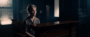 Movie still from “The Judge” (2014), directed by David Dobkin – An older woman sitting at a piano in a dark room; Medium shot, Low angle