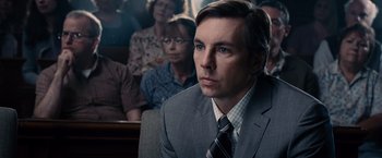 Movie still from “The Judge” (2014), directed by David Dobkin – A man in a suit and tie sitting in front of other people; Close Up shot, Over the shoulder angle