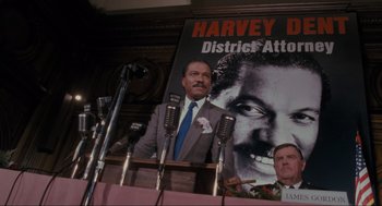 Movie still from “Batman” (1989), directed by Tim Burton – A man is speaking at a political event; Medium shot, High angle