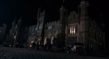 Movie still from “Batman” (1989), directed by Tim Burton – A group of cars parked in front of a large building at night; Extreme Wide shot, Low angle