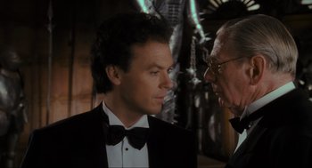 Movie still from “Batman” (1989), directed by Tim Burton – A man in a tuxedo talking to another man in a suit; Close Up shot, Over the shoulder angle