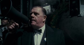 Movie still from “Batman” (1989), directed by Tim Burton – An older man in a tuxedo smoking a cigarette; Close Up shot, Low angle