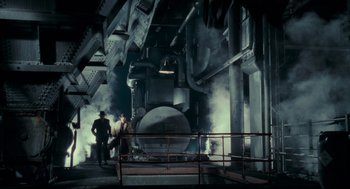 Movie still from “Batman” (1989), directed by Tim Burton – Two men standing in front of an old steam engine; Wide shot, Low angle