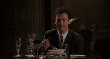 Movie still from “Batman” (1989), directed by Tim Burton – A man sitting at a table with a plate in front of him; Medium shot, Low angle