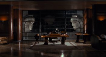 Movie still from “Batman” (1989), directed by Tim Burton – A man sitting at a desk in front of a window; Wide shot, High angle