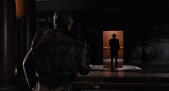 Movie still from “Batman” (1989), directed by Tim Burton – A man standing in front of an open door; Wide shot, Over the shoulder angle
