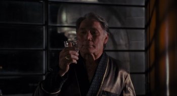 Movie still from “Batman” (1989), directed by Tim Burton – An older man holding a wine glass and smoking a cigarette; Close Up shot, Low angle