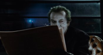 Movie still from “Batman” (1989), directed by Tim Burton – A man with a joker make - up looking at a piece of paper; Close Up shot, Over the shoulder angle