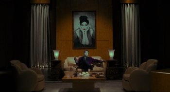 Movie still from “Batman” (1989), directed by Tim Burton – A man sitting on a couch in front of a painting; Wide shot, Low angle