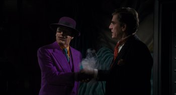 Movie still from “Batman” (1989), directed by Tim Burton – A man in a purple suit shaking hands with another man in a black suit; Medium shot, Over the shoulder angle