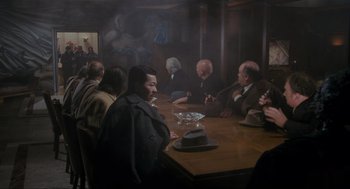 Movie still from “Batman” (1989), directed by Tim Burton – A group of people sitting around a table; Wide shot, High angle