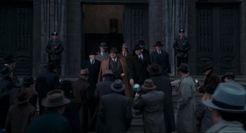 Movie still from “Batman” (1989), directed by Tim Burton – A group of men in suits and hats standing on steps; Wide shot, Low angle
