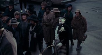 Movie still from “Batman” (1989), directed by Tim Burton – A group of people standing around a man in a top hat; Wide shot, High angle