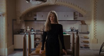 Movie still from “Batman” (1989), directed by Tim Burton – A woman in a black dress standing in a kitchen; Medium shot, Low angle