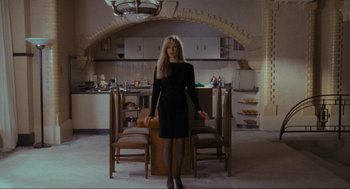 Movie still from “Batman” (1989), directed by Tim Burton – A woman standing in front of a table in a kitchen; Wide shot, High angle