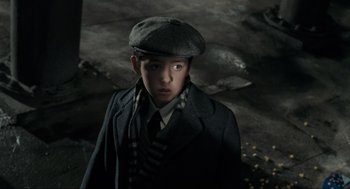 Movie still from “Batman” (1989), directed by Tim Burton – A young boy in a hat and a coat; Close Up shot, High angle