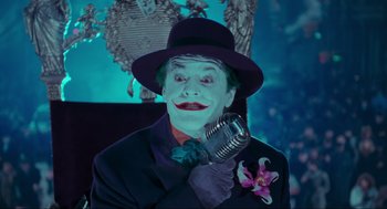 Movie still from “Batman” (1989), directed by Tim Burton – A man in a suit and hat holding a microphone; Medium shot, Low angle