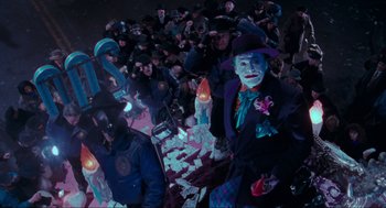 Movie still from “Batman” (1989), directed by Tim Burton – A group of people sitting around a table with money on top of it; Wide shot, High angle