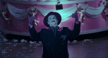 Movie still from “Batman” (1989), directed by Tim Burton – A man dressed as the joker in a suit and hat; Medium shot, Low angle
