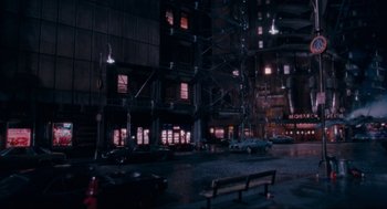 Movie still from “Batman” (1989), directed by Tim Burton – A city street with a bench and cars parked on the side of the street; Extreme Wide shot, High angle