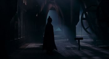 Movie still from “Batman” (1989), directed by Tim Burton – A man dressed as batman walking in a dark place; Wide shot, Over the shoulder angle