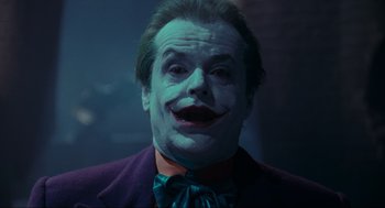 Movie still from “Batman” (1989), directed by Tim Burton – A person wearing a joker mask; Close Up shot, Low angle