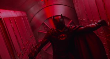 Movie still from “Batman Forever” (1995), directed by Joel Schumacher – A man dressed as a batman in a red room; Wide shot, Overhead angle