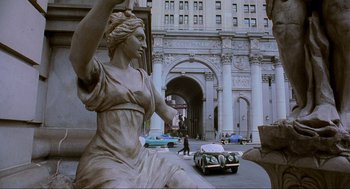 Movie still from “Batman Forever” (1995), directed by Joel Schumacher – A statue of a woman in front of an old building; Extreme Wide shot, High angle