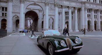 Movie still from “Batman Forever” (1995), directed by Joel Schumacher – An old car parked on the side of the street; Extreme Wide shot, High angle