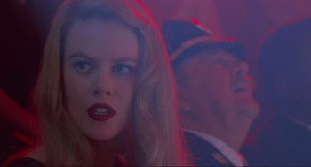 Movie still from “Batman Forever” (1995), directed by Joel Schumacher – A beautiful woman with blue eyes and red lipstick; Close Up shot, Over the shoulder angle