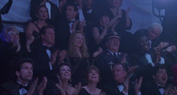 Movie still from “Batman Forever” (1995), directed by Joel Schumacher – A group of people sitting and standing in a room; Medium shot, Over the shoulder angle