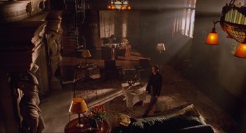 Movie still from “Batman Forever” (1995), directed by Joel Schumacher – A woman standing in a living room in a room with furniture; Extreme Wide shot, High angle