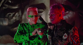 Movie still from “Batman Forever” (1995), directed by Joel Schumacher – A man and a woman dressed up as riddler and joker; Medium shot, Low angle