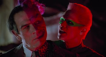 Movie still from “Batman Forever” (1995), directed by Joel Schumacher – Two men in costumes one of which has a flower in his hair and the other has a pink flower in his hair; Close Up shot, Over the shoulder angle
