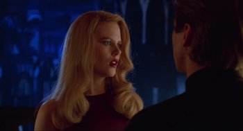 Movie still from “Batman Forever” (1995), directed by Joel Schumacher – A woman with long blonde hair standing next to a man; Close Up shot, Over the shoulder angle