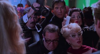 Movie still from “Batman Forever” (1995), directed by Joel Schumacher – A group of people gathered around each other in a room; Close Up shot, Low angle
