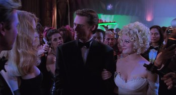 Movie still from “Batman Forever” (1995), directed by Joel Schumacher – A man and a woman in formal wear at an event; Medium shot, Low angle