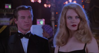 Movie still from “Batman Forever” (1995), directed by Joel Schumacher – A man and a woman standing next to each other in front of lights; Close Up shot, Over the shoulder angle