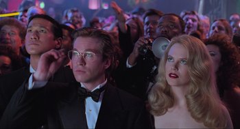 Movie still from “Batman Forever” (1995), directed by Joel Schumacher – A man and a woman in front of an audience; Medium shot, Low angle