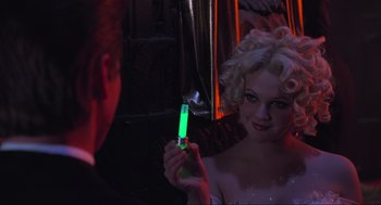 Movie still from “Batman Forever” (1995), directed by Joel Schumacher – A woman holding a cell phone in front of a man; Close Up shot, Over the shoulder angle
