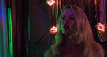 Movie still from “Batman Forever” (1995), directed by Joel Schumacher – A beautiful blonde woman with long hair and pink lights; Close Up shot, Low angle