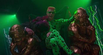 Movie still from “Batman Forever” (1995), directed by Joel Schumacher – A man in a green suit and pink wig; Medium shot, High angle