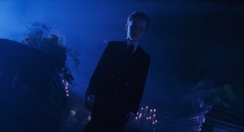 Movie still from “Batman Forever” (1995), directed by Joel Schumacher – A man in a suit and tie standing in the dark at night; Wide shot, Low angle