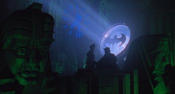 Movie still from “Batman Forever” (1995), directed by Joel Schumacher – Two men sitting in front of a projection of batman logo; Wide shot, Low angle