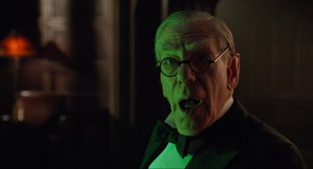 Movie still from “Batman Forever” (1995), directed by Joel Schumacher – An old man in a suit and glasses with his mouth wide open; Close Up shot, Low angle