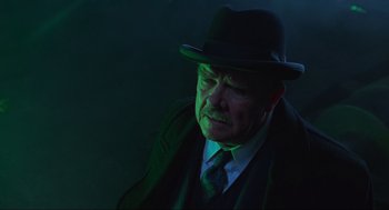 Movie still from “Batman Forever” (1995), directed by Joel Schumacher – An old man wearing a hat and a tie; Close Up shot, Low angle