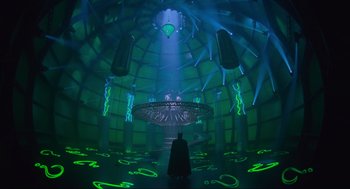 Movie still from “Batman Forever” (1995), directed by Joel Schumacher – A man dressed as batman standing in front of a green light; Extreme Wide shot, High angle