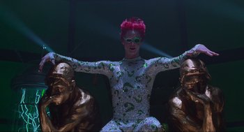 Movie still from “Batman Forever” (1995), directed by Joel Schumacher – A woman with pink hair sitting on a statue; Medium shot, Low angle