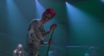 Movie still from “Batman Forever” (1995), directed by Joel Schumacher – A man with pink hair holding a green cane; Medium shot, Low angle